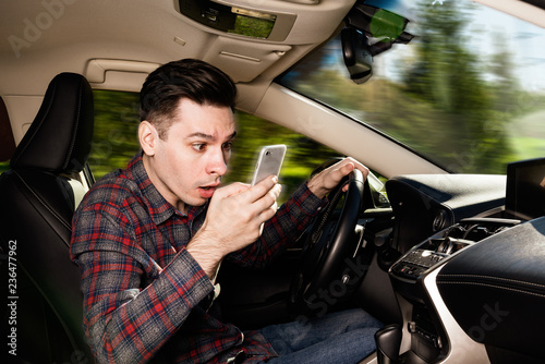 Obraz na płótnie Man sitting inside car with mobile phone in hand texting while driving w salonie