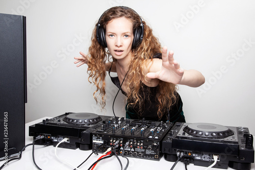 Portrait of curly hair young DJ playing music on light background