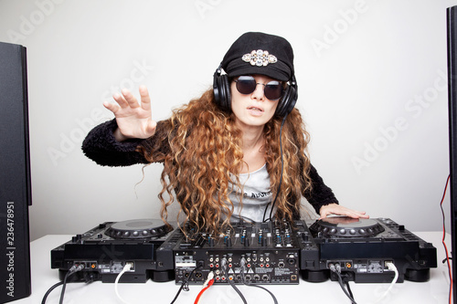 Portrait of curly hair young DJ playing music on light background