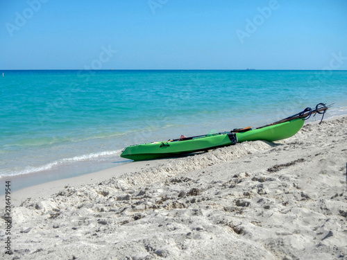 Green outrigger canoe on a sandy beach and blue sky in Hawaii 