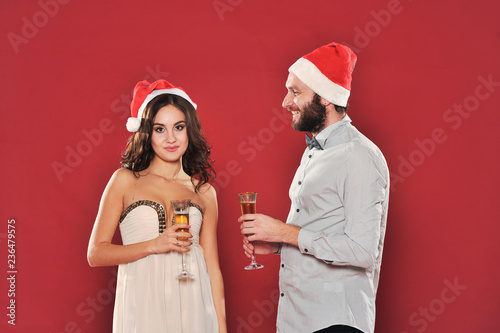 Young lovely couple with glass in Santa hats