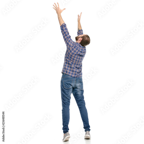 Tapeta A man in jeans hands up holding taking looking up on a white background