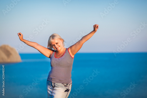 half body portrait of young woman enjoying breeze at beach. Portrait of carefree girl relaxing at sea. Beautiful smiling woman enjoying at beach the sun.