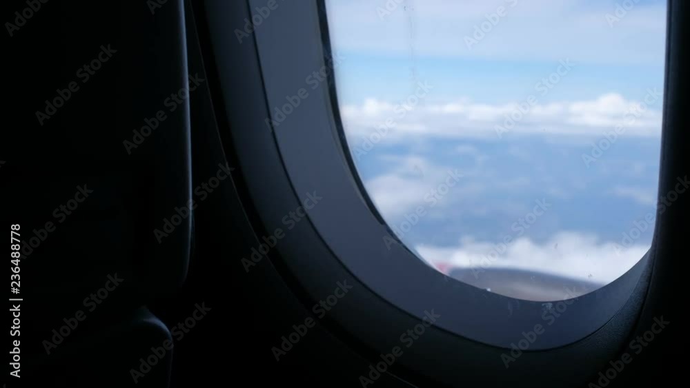 Clouds and sky as seen through window of an aircraft flying, plane window view with blue sky and clouds. Royalty high-quality free stock video footage of view from airplane window sky view on the wing Clouds and sky as seen through window of an aircraft flying, plane window view with blue sky and clouds. Royalty high-quality free stock video footage of view from airplane window sky view on the wing