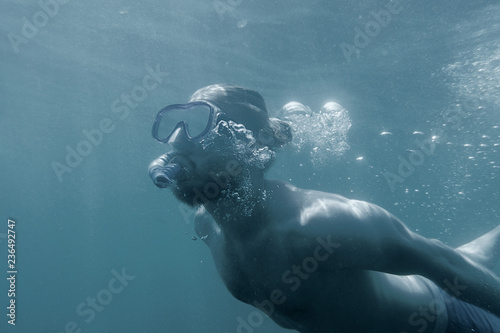 Sporty man snorkeling underwater.