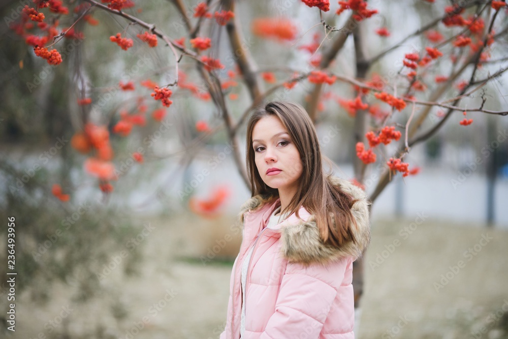 Beautiful young girl in white sweater and pink jacket walking in the Park. Beautiful young girl in white sweater and pink jacket walking in the Park.