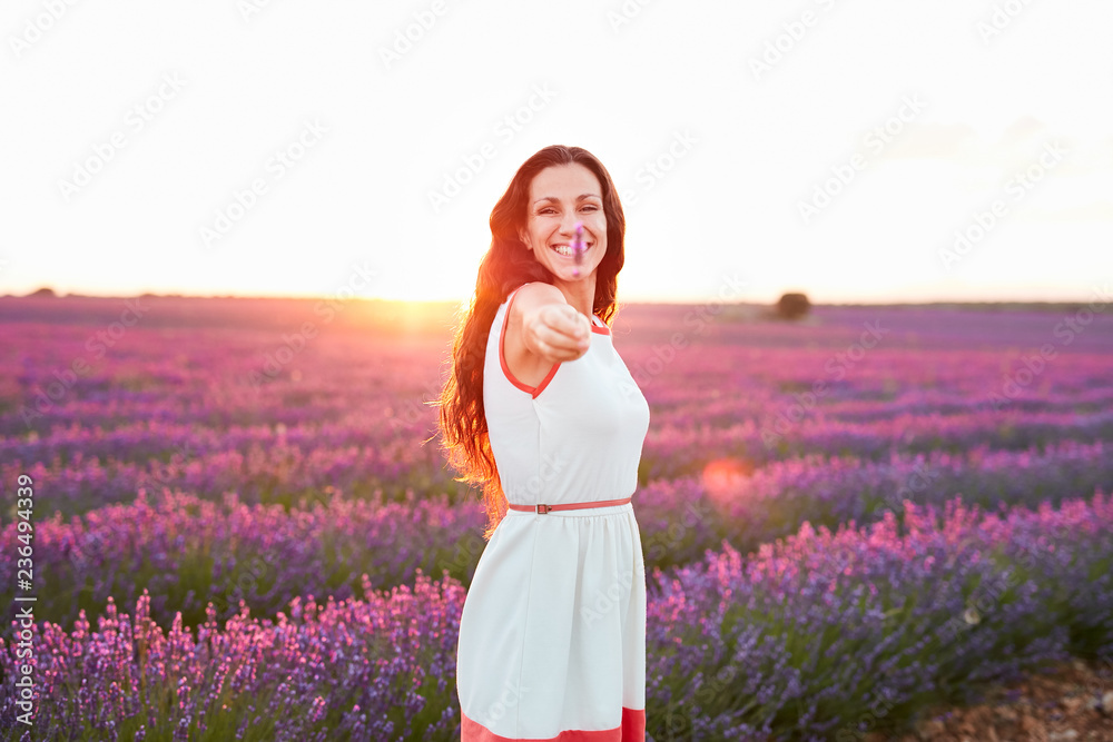 Smiling young woman showing flower between violet lavender field Smiling young woman showing flower between violet lavender field