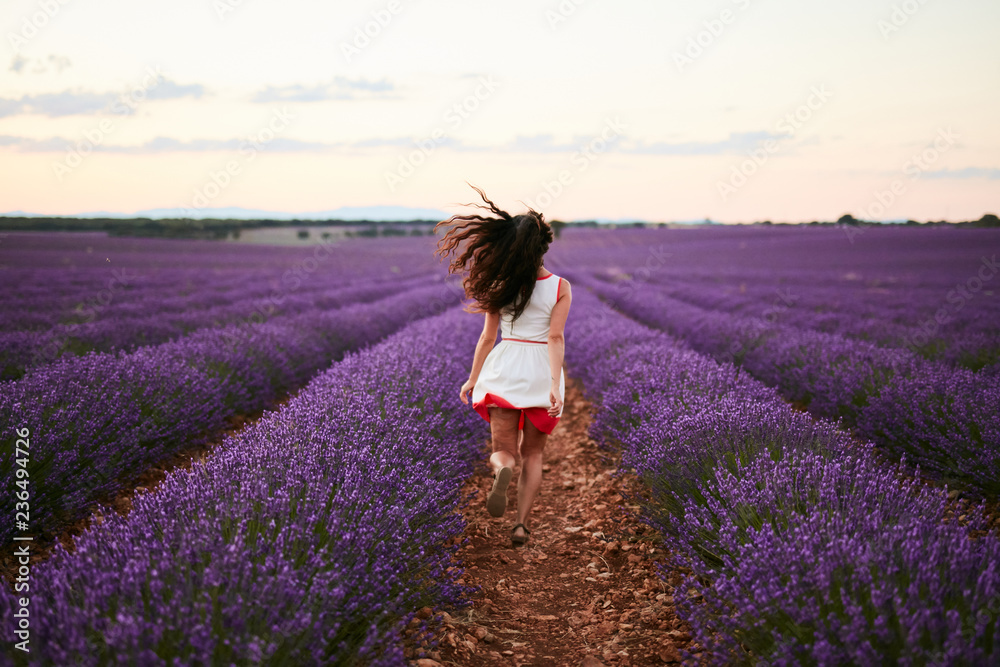 Young woman running between violet lavender field Young woman running between violet lavender field