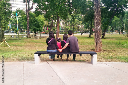 young family sitting on a bench in park