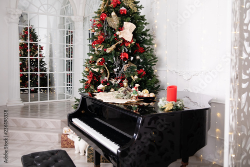 Christmas tree decorated with toys, lights and garland and piano