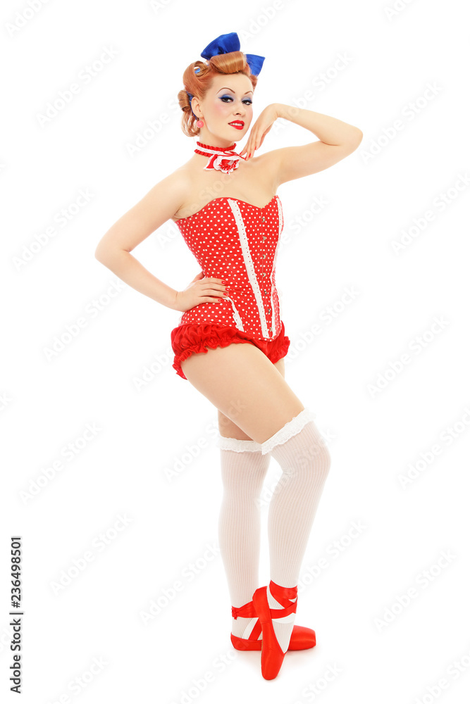 Young beautiful sexy pin-up girl in polka dot corset and red ballet shoes over white background