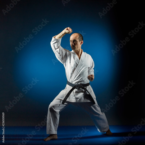 Adult athlete trains formal exercises on blue tatami