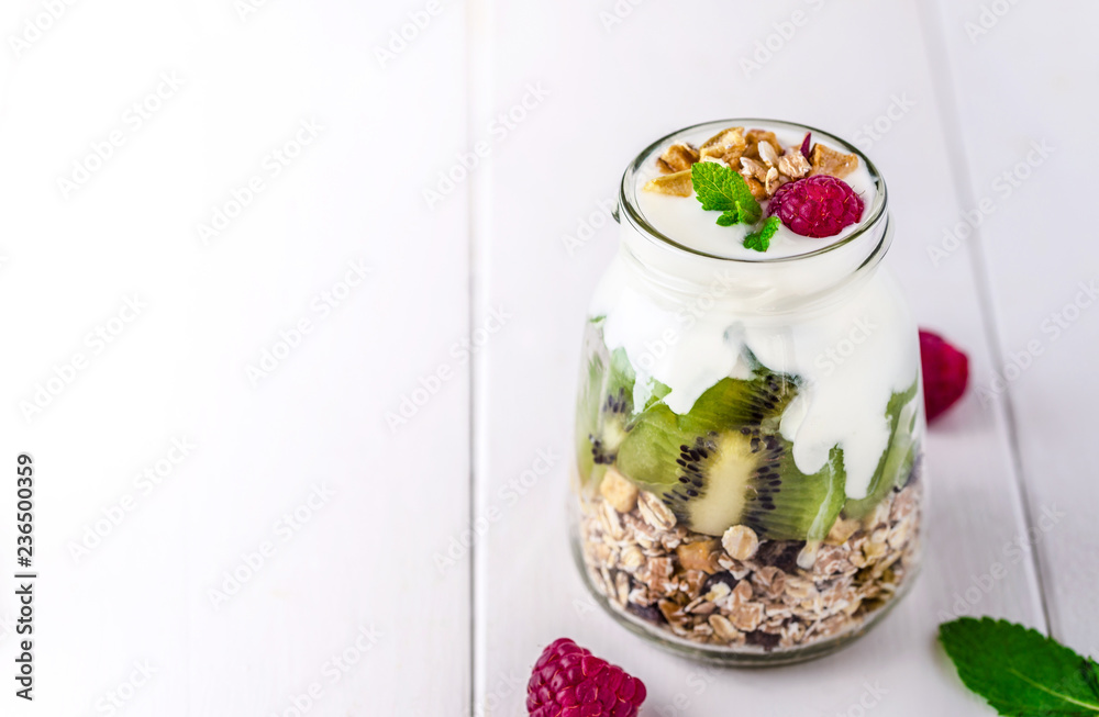 White yogurt with muesli in glass bowl with pieces of kiwi on the top. White yogurt with muesli in glass bowl with pieces of kiwi on the top.