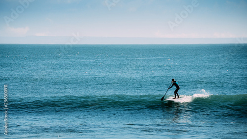 Silhouette of unidentifiable man castching a wave while on a stand up paddle board © Alexandre Rotenberg