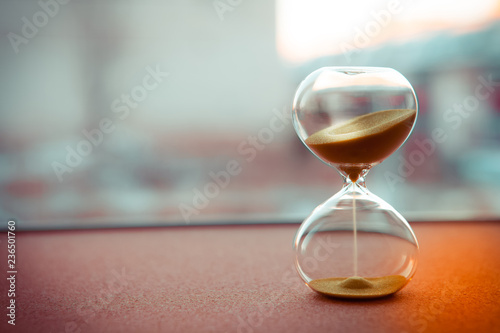 Sand running through the bulbs of an hourglass measuring the passing time in a countdown to a deadline, on a blur background