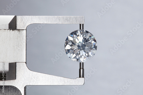 loose big brilliant round diamond is being measure by mm gauge and weight estimator for size photo