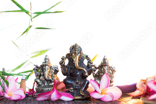 Statue of Ganesha Indian Hinduism God of wisdom and prosperity and heap of plumeria frangipani flowers