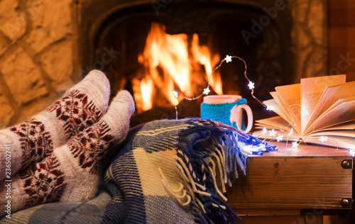 Woman's legs with mug cup of tea near fireplace