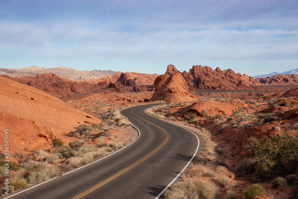 Scenic view on the road in the desert during a cloudy and sunny day. Taken in Valley of Fire State Park, Nevada, United States. Scenic view on the road in the desert during a cloudy and sunny day. Taken in Valley of Fire State Park, Nevada, United States.