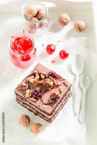 Chocolate cake with cherries and walnuts on white table