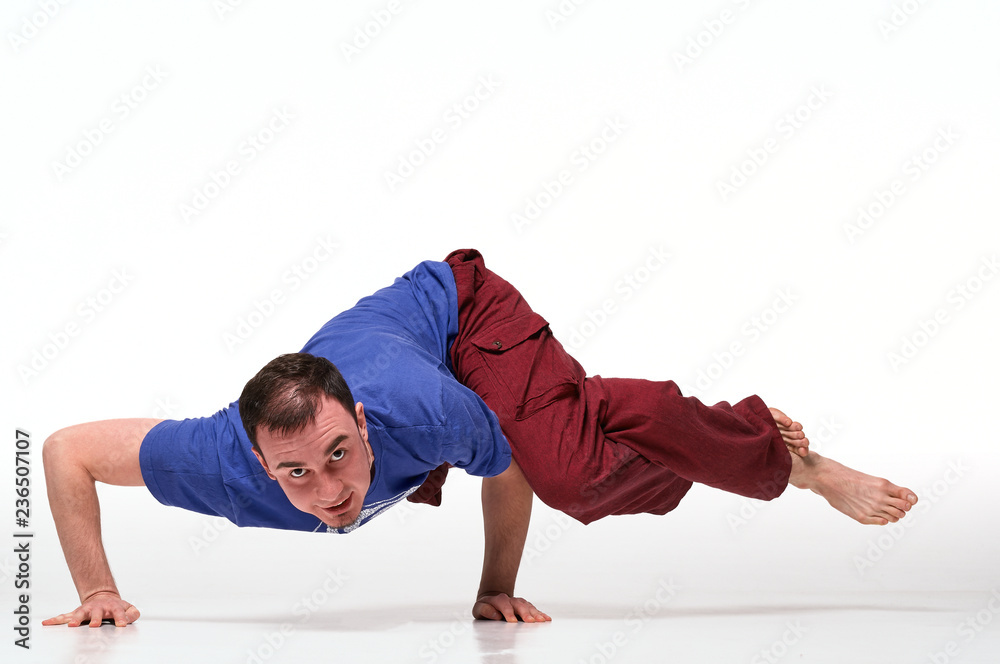 Sporty attractive young man working out, yoga, pilates, fitness training, asana Dwi pada kaundiniasana isolated on white. Studio shot. Full length