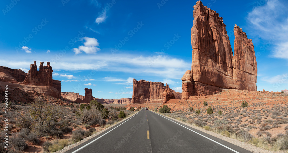 Panoramic Landscape view of a Scenic road in the red rock canyons during a vibrant sunny day. Taken in Arches National Park, located near Moab, Utah, United States. Panoramic Landscape view of a Scenic road in the red rock canyons during a vibrant sunny day. Taken in Arches National Park, located near Moab, Utah, United States.