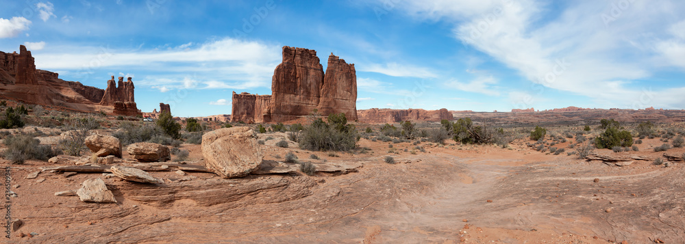 Panoramic landscape view of beautiful red rock canyon formations during a vibrant sunny day. Taken in Arches National Park, located near Moab, Utah, United States.