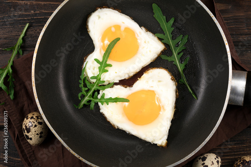 Fried eggs in the pan on wooden background