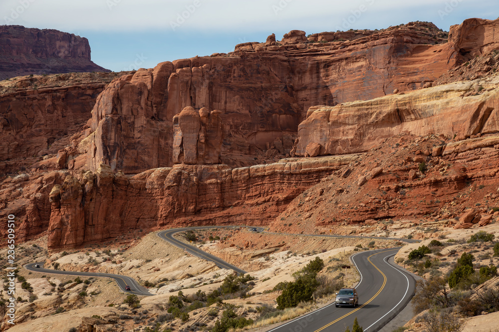 Scenic road in the red rock canyons during a vibrant sunny day. Taken in Arches National Park, located near Moab, Utah, United States.