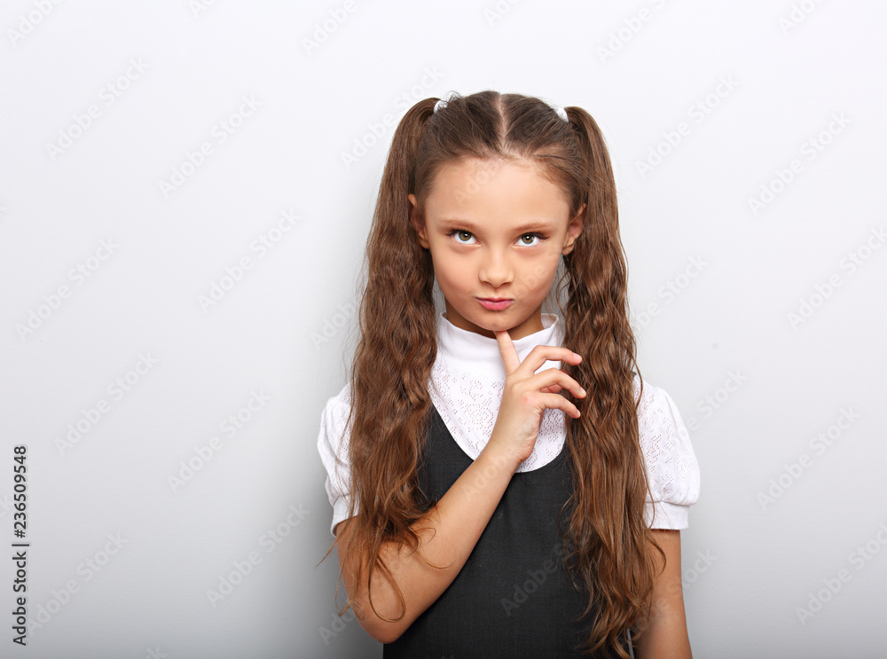 Fun pupil girl school uniform thinking and looking up on blue background with empty copy space Fun pupil girl school uniform thinking and looking up on blue background with empty copy space