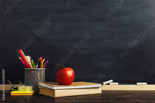 Teacher's desk with writing materials, a book and an apple, a blank for text or a background for a school theme. Copy space. photo