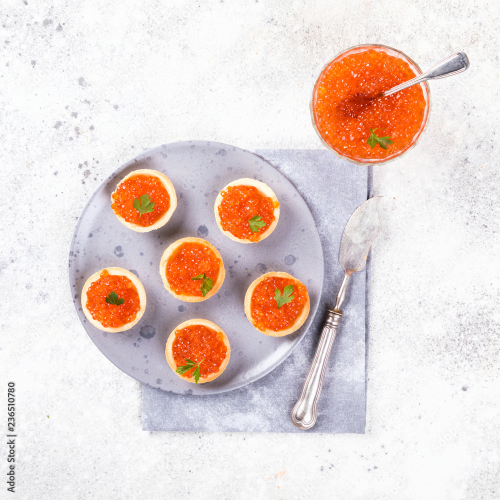 Holidays composition. Red Salmon Caviar in tartlet on a plate. Festive Appetizer on gray background.Copy space for Text. Holidays composition. Red Salmon Caviar in tartlet on a plate. Festive Appetizer on gray background.Copy space for Text.