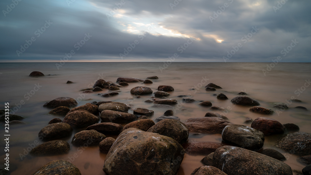 storm clouds forming over clear sea beach with rocks and clear sand