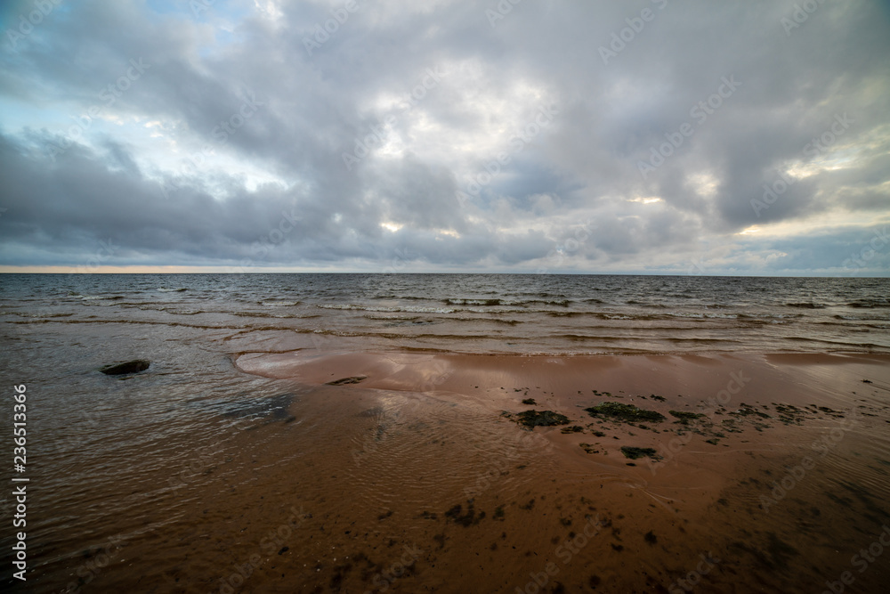 storm clouds forming over clear sea beach with rocks and clear sand
