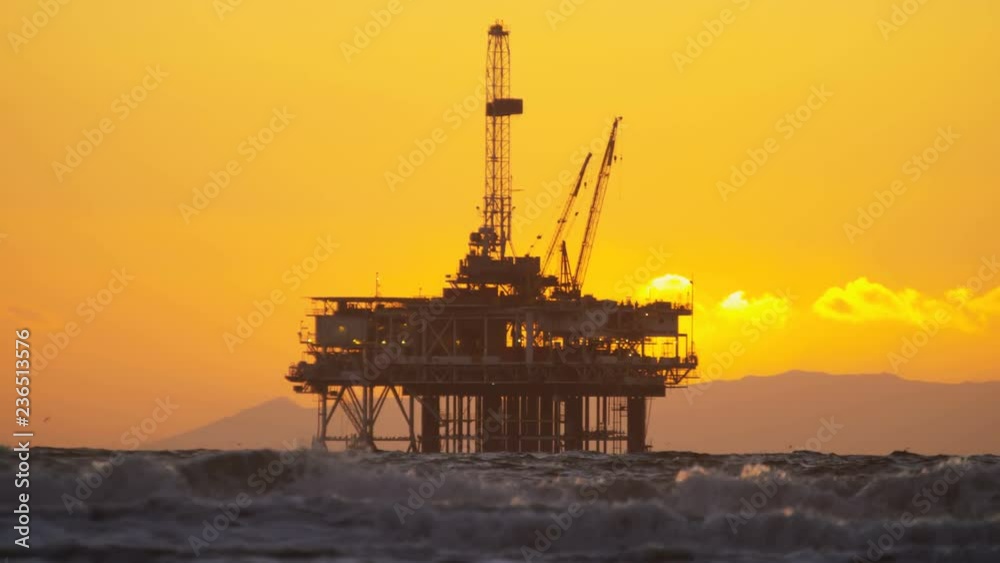 Silhouette of Oil rig coastal platform at sunset drilling for fuel Pacific coastline slow motion California USA  