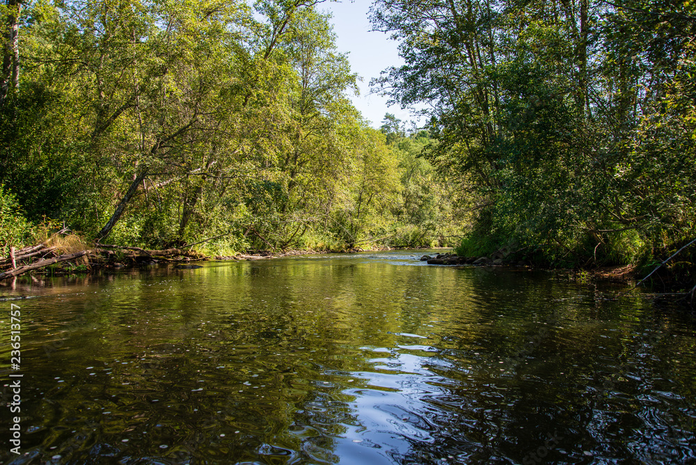 summer day on water in calm river enclosed in forests with sandstone cliffs and dry wood summer day on water in calm river enclosed in forests with sandstone cliffs and dry wood