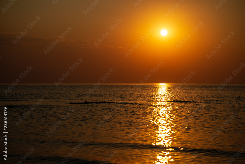 dramatic red orange colored sunset over the calm sea at summer