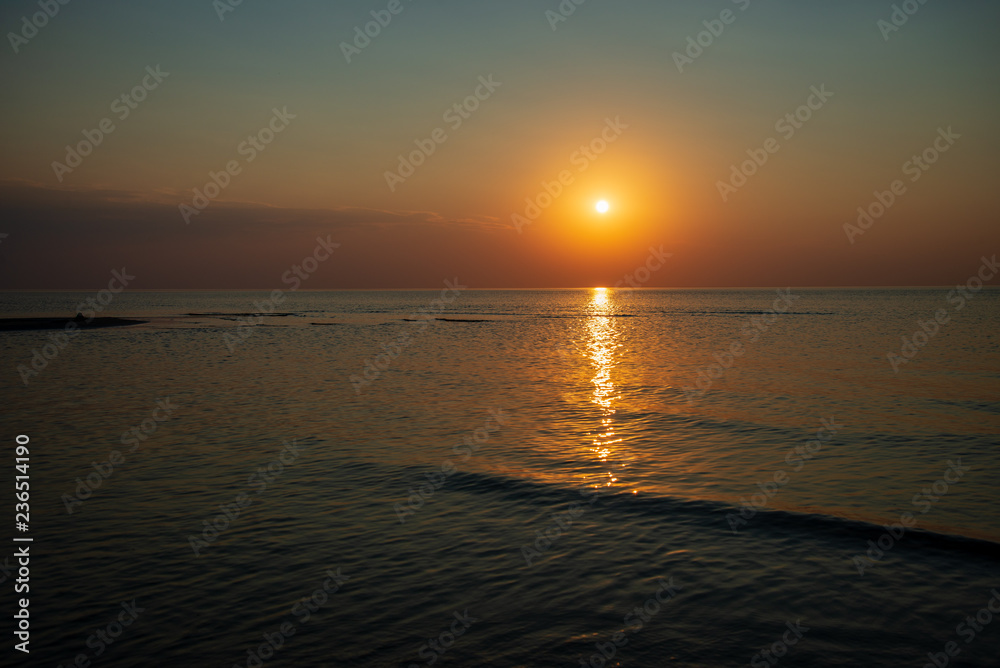 Naklejka premium dramatic red orange colored sunset over the calm sea at summer