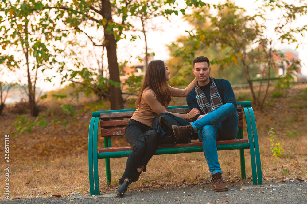 Angry boyfriend refusing to talk to his beautiful girlfriend,while sitting in a park.