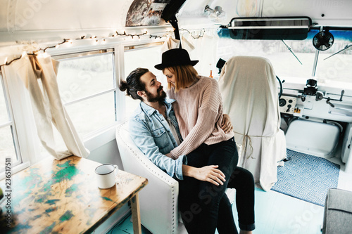 Cute hipster couple cuddling in converted school bus tiny home photo