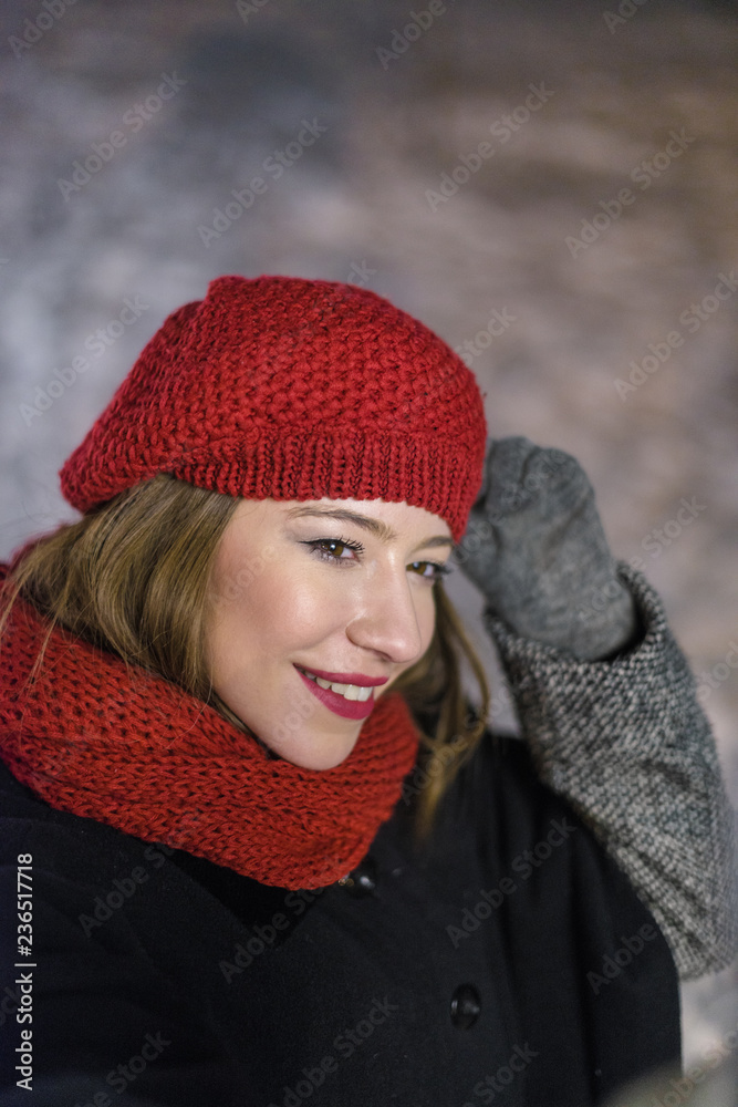Red hat girl standing in front of christmas tree lights taking photo of herself at night Red hat girl standing in front of christmas tree lights taking photo of herself at night