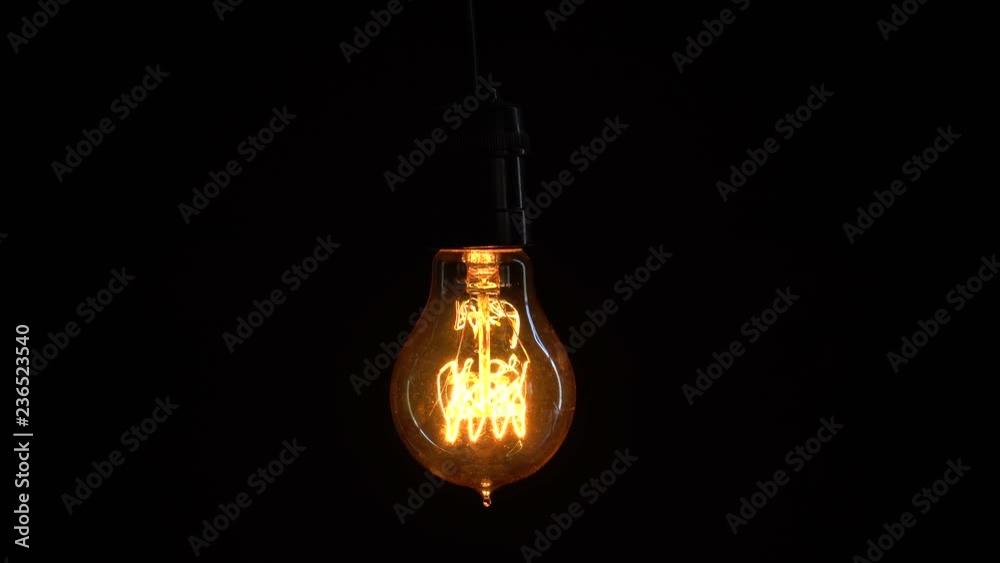 Power saving concept. Light bulb turns on and off over black background in the studio. Shot in 4k resolution