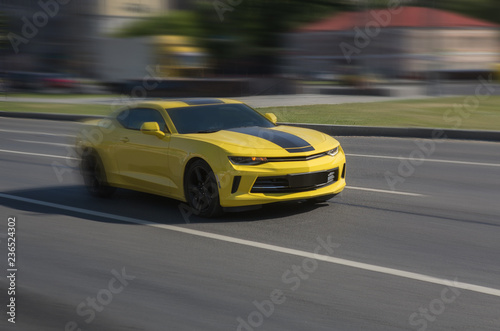Yellow sports car racing down the city street © Yuri Bizgaimer