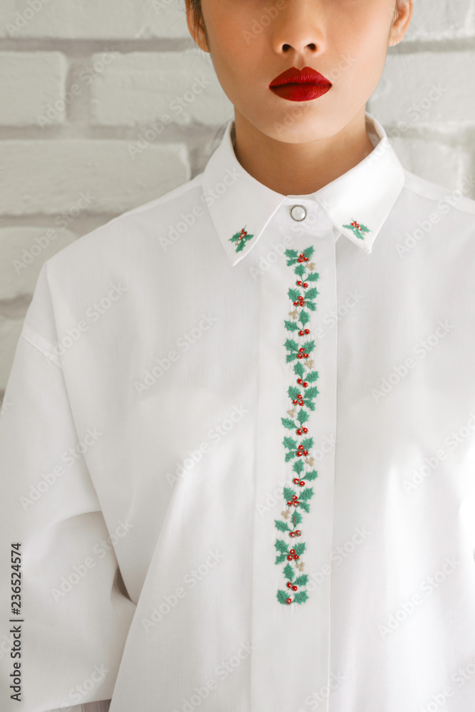 © Nabi Tang/Stocksy - Red lips woman portrait in white Christmas embroidered shirt © Nabi Tang/Stocksy - Red lips woman portrait in white Christmas embroidered shirt