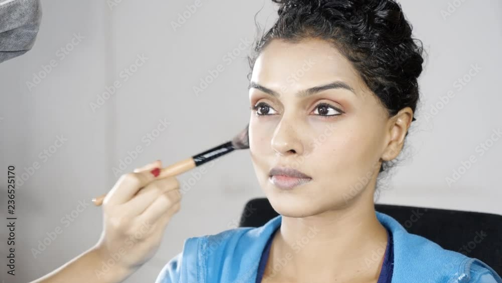 Makeup artist applying makeup on beautiful young woman cheek in makeup room. Shot in 4k resolution Makeup artist applying makeup on beautiful young woman cheek in makeup room. Shot in 4k resolution