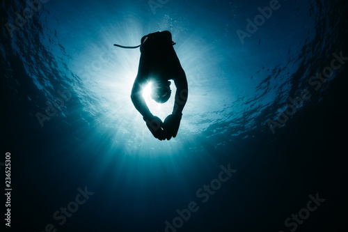 Diver swimming underwater in bright sunlight