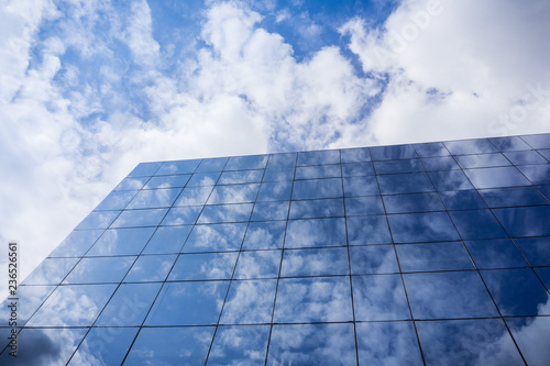 White clouds reflected on the facade of a modern office building on a sunny day