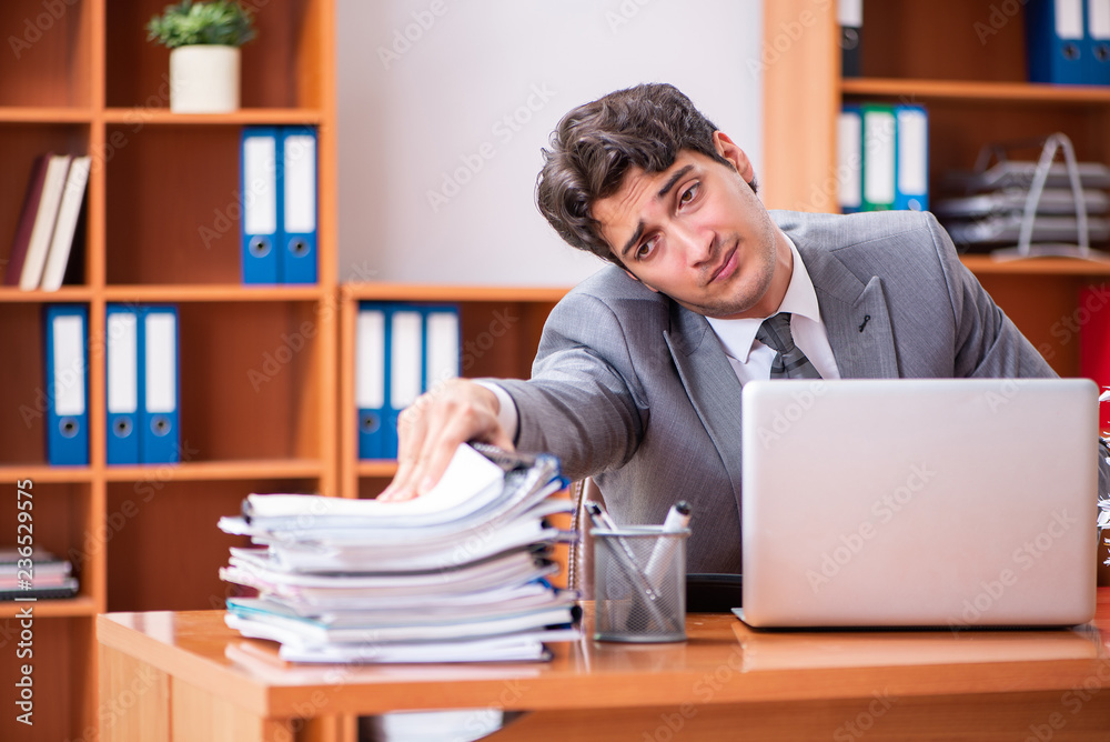 Young handsome businessman unhappy with excessive work 
