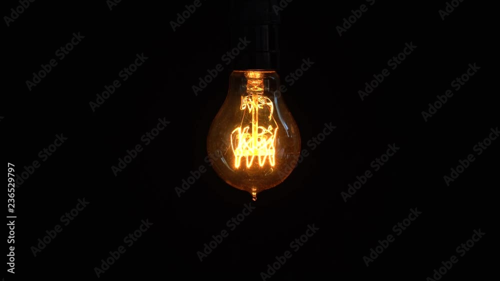 Power saving concept. Old light bulb glowing on dark background in the studio. Shot in 4k resolution Power saving concept. Old light bulb glowing on dark background in the studio. Shot in 4k resolution