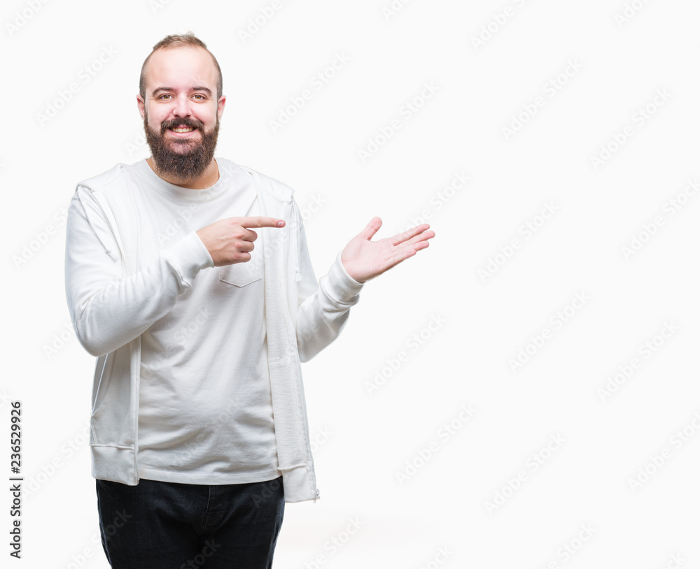 Young caucasian hipster man wearing sport clothes over isolated background amazed and smiling to the camera while presenting with hand and pointing with finger.